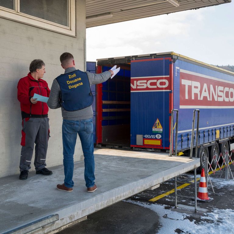 Mitarbeiter von Zoll und Spedition auf der Rampe vor einem Transco Lkw